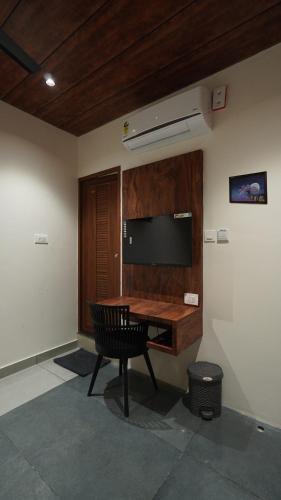 a room with a desk and a television on the wall at Hotel Hive Inn - Kozhikode in Kozhikode