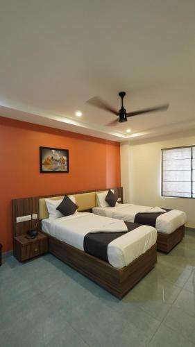 two beds in a room with orange walls at Hotel Hive Inn - Kozhikode in Kozhikode