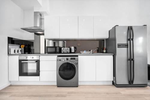 a kitchen with a refrigerator and a washing machine at Apartment - Secure Parking - Gated Development - Near JQ & Birmingham City Centre - Top Rated - Flower Wall - 12SH in Birmingham