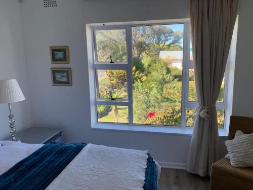 a bedroom with a bed and a large window at Your own space in the leafy Cape in Cape Town