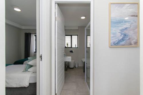 a hallway leading to a bedroom with a bed and a bathroom at Bella Mare 13 on Boardwalk in Gqeberha