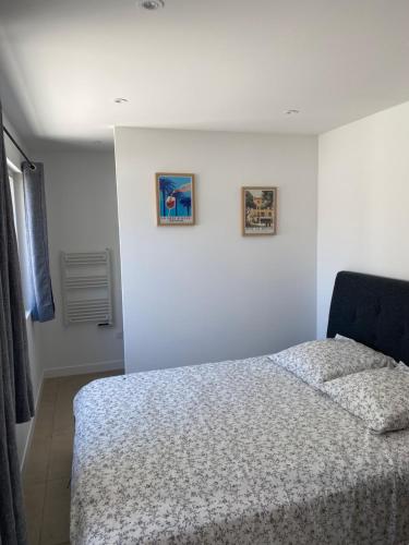 une chambre avec un lit et deux tableaux au mur dans l'établissement T2 cosy et au calme, à Saint-Rémy-de-Provence