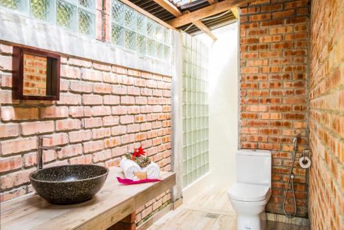 a brick walled bathroom with a sink and a toilet at The Dusun in Seremban