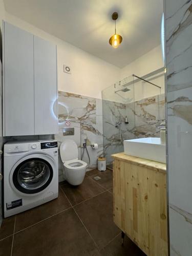 a bathroom with a washing machine and a toilet at Saint 40 Suites Premium Flat in Sarandë
