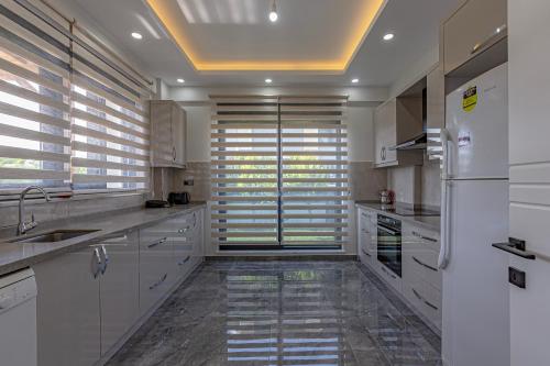 a large kitchen with white cabinets and a refrigerator at Villa Tosun in Belek