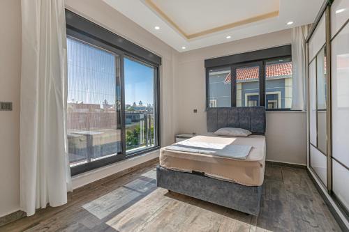 a bedroom with a bed and large windows at Villa Tosun in Belek