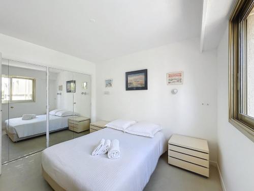- 2 lits dans une chambre avec des murs blancs et des miroirs dans l'établissement 2 bedroom apartment with parking 3 mins from La Croisette beach, à Cannes