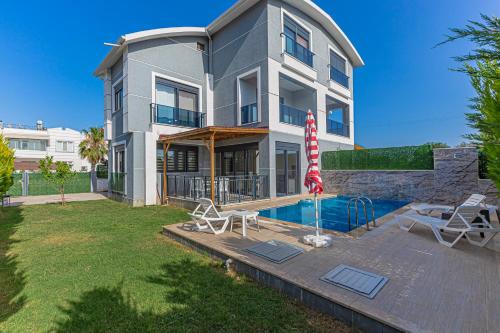 a house with a swimming pool and an umbrella at Villa Tosun in Belek