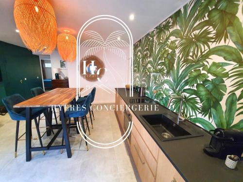 d'une salle à manger avec une table et un papier peint tropical. dans l'établissement Le Bois d'Olivier T2 à Giens CLiM WiFi Parking By HC, à Hyères