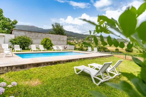 a villa with a swimming pool and lounge chairs at Casa da Professora Ponte de Lima in Refoios do Lima
