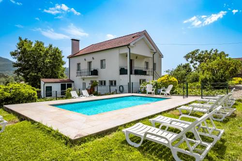 a villa with a swimming pool in front of a house at Casa da Professora Ponte de Lima in Refoios do Lima