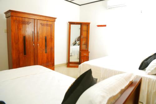 a bedroom with two beds and a cabinet and a mirror at Bella Vista Villa in Seeduwa