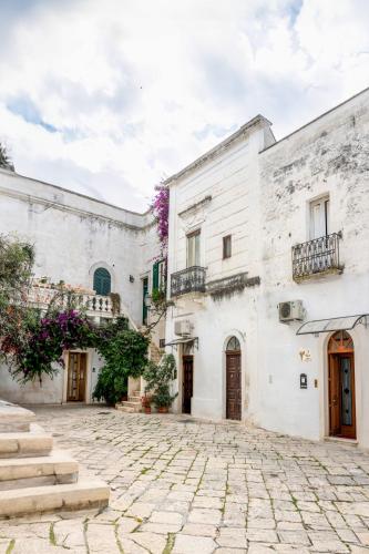 a courtyard of a white building with purple flowers at Il Tulipano Rosso in Oria