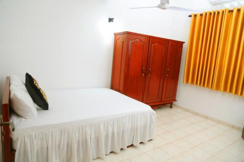 a bedroom with a bed and a wooden cabinet at Bella Vista Villa in Seeduwa