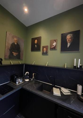 a bathroom with portraits of people on the wall at Appartement 2pers «Le Parisien » in Saint-Omer