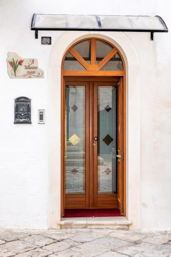 a wooden door on a white building with glass at Il Tulipano Rosso in Oria