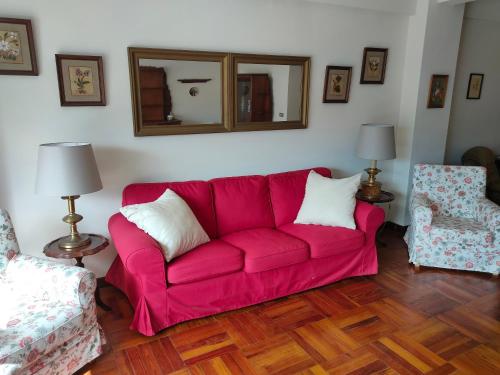 a pink couch in a living room with two chairs at La Casa de la Abuela Boticaria in Redondela