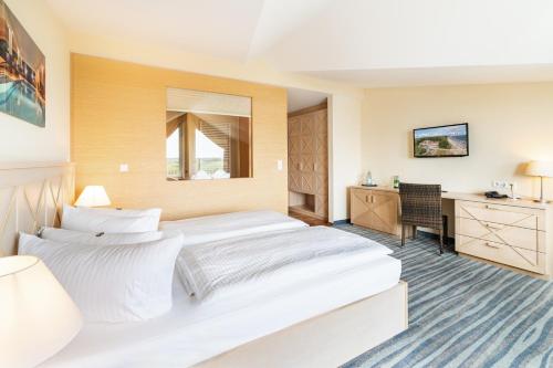 a hotel room with two beds and a desk at Strandhotel Seerose in Kolpinsee