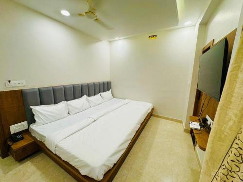 a bedroom with a large bed with white sheets at Hotel Najaf Palace in Ajmer