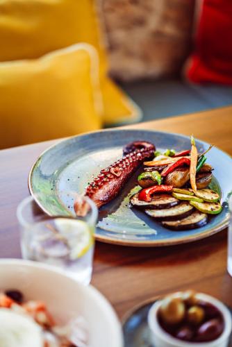 a plate of food with sausage and vegetables on a table at Petunia Ibiza, a Beaumier hotel in Cala Vadella
