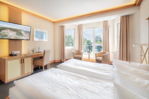 a hotel room with a bed and a desk at Strandhotel Seerose in Kolpinsee