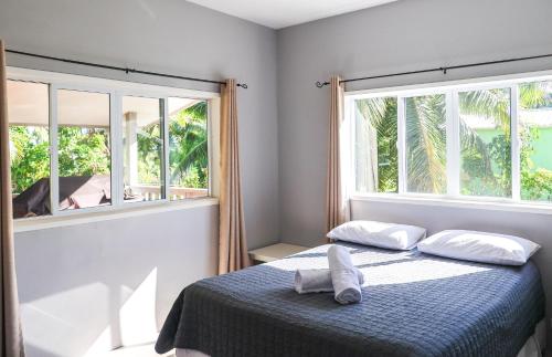 una camera da letto con un letto con due cuscini e due finestre di Inave Holidays a Rarotonga