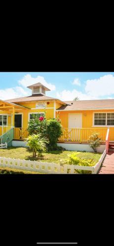 a large yellow house with a porch at Nathan's Lodge in Kemps Bay
