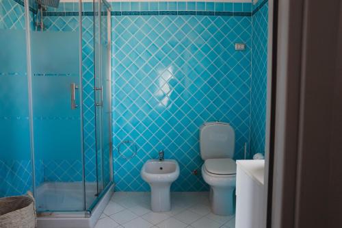 a blue tiled bathroom with a toilet and a shower at Cactus Mare Apartment in Golfo Aranci