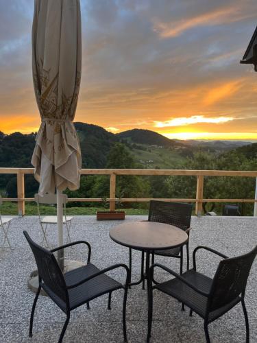 patio con tavolo, sedie e ombrellone di Karla’s House a Dobje pri Planini