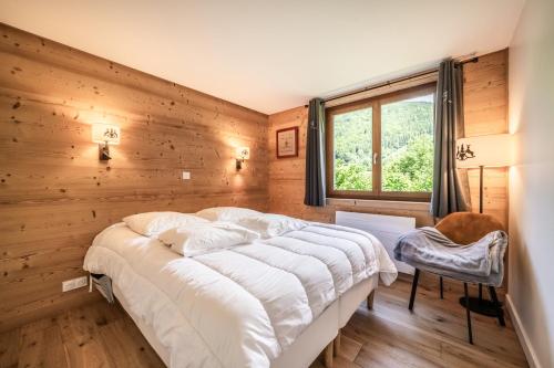 - un grand lit dans une chambre dotée d'un mur en bois dans l'établissement Ressachaux B2 Appartement 2 chambres entièrement refait à neuf, à Morzine