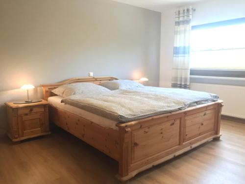 een slaapkamer met een groot houten bed en een raam bij Maxi-Apartment Bodanum - mit eigener Terrasse - naturnahe Ortsrandlage - VDSL - 10 min zum Nürburgring in Bodenbach