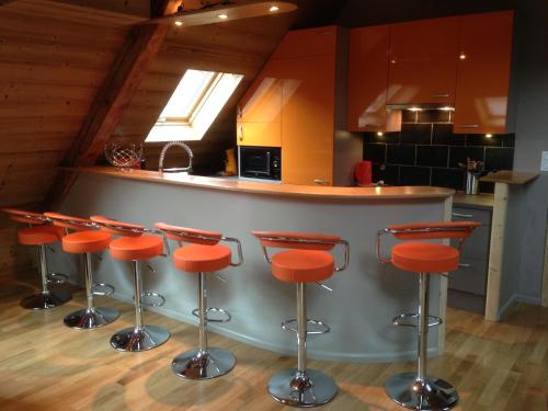 - une cuisine avec un bar avec des tabourets orange dans l'établissement Les Combles - Saint Etienne de Cuines, à Saint-Étienne-de-Cuines