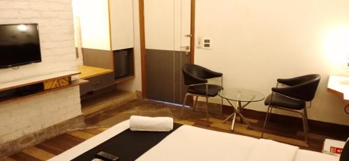 a room with two chairs and a tv and a table at Stays - Golf Course Road in Gurgaon