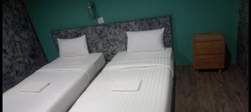 two twin beds in a room with a green wall at เซราะกราว บูติก รีสอร์ท Sohground Boutique Resort in Prakhon Chai
