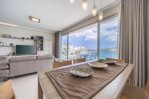 a living room with a table and a large window at Avalon by the Sea - A Breath of Oceanfront Luxury in Sliema