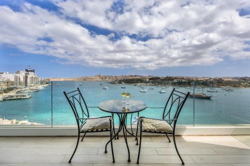 a table and chairs with a view of the water at Avalon by the Sea - A Breath of Oceanfront Luxury in Sliema