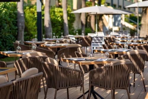an outdoor restaurant with tables and chairs and umbrellas at Valentin Star Menorca - Adults Only in Cala'n Bosch