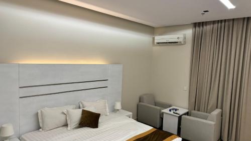 a bedroom with a bed and two chairs at فندق قمم الصفوه الفندقيه in Rafha