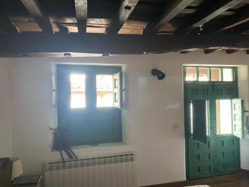 a room with two windows and a green door at Casa Rural Cerro del Mariscal in Sequeros