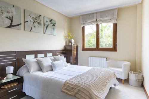 a bedroom with a large white bed and a chair at Apartamento en Badames con piscina comunitario in Bádames