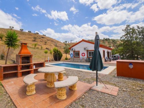 a backyard with a pool and an umbrella and a house at Cubo's Casa Rural El Andaluz in Villafranco de Guadalhorce