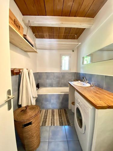 La salle de bains est pourvue d'une baignoire, d'un lavabo et d'un lave-linge. dans l'établissement Jolie villa avec jardin terrasses jacuzzi 15mins plages - MONTPELLIER, à Pignan