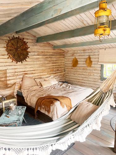 a hammock in a log cabin bedroom with a bed at Bamboo Lodge Groningen in Groningen