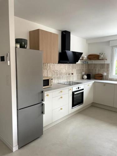  La cuisine est équipée de placards blancs et d'un réfrigérateur. dans l'établissement Appartement luxueux à 3 min des plages, à Torreilles