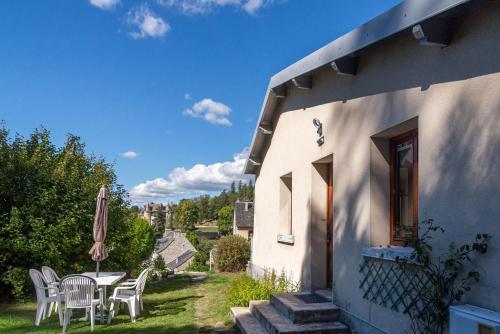 a house with a table and chairs and an umbrella at La maison rocher in Fournels