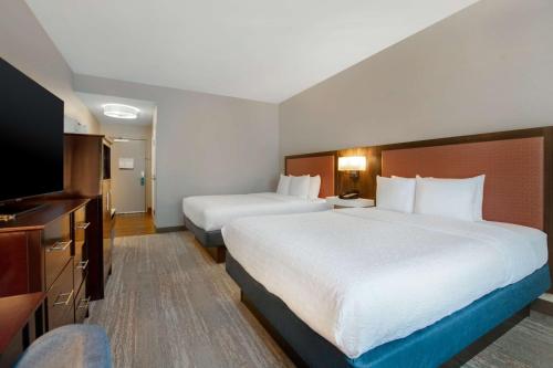 a hotel room with two beds and a flat screen tv at Hampton Inn & Suites Harvey New Orleans Westbank in Harvey