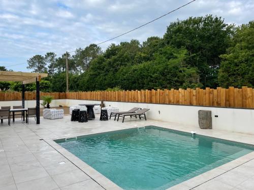 - une piscine sur une terrasse avec une table et des chaises dans l'établissement Petit paradis, à Soustons