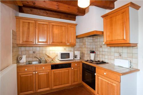 La cuisine est équipée de placards en bois, d'un évier et d'un four micro-ondes. dans l'établissement Gites de france 3 epis 8 personnes a conques les genevriers, à La Canourgue