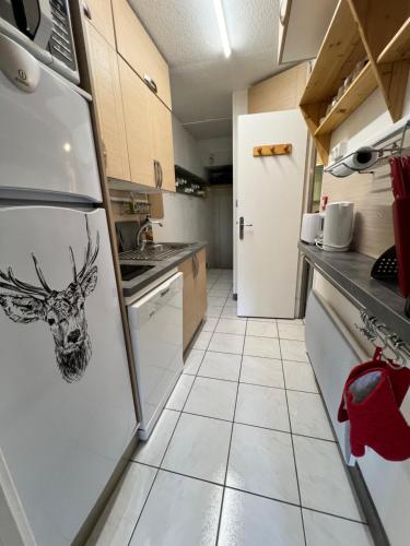une cuisine avec un réfrigérateur avec une tête de cerf dessus dans l'établissement T2 6 personnes Superdevoluy Les Issarts aux pieds des pistes orientation sud, à Superdevoluy