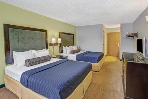 a hotel room with two beds and a flat screen tv at Days Inn by Wyndham Great Lakes Naval Base in North Chicago